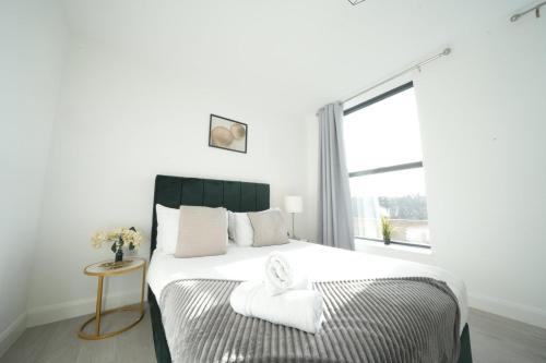 a white bedroom with a large bed with a window at Ealing Broadway Great Stay 7-Minute Walk from the Underground in Ealing