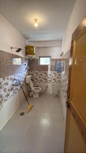 a bathroom with a toilet and a mop at Resort Apple County by Himalayan Hotels- Mountain View, Parking & Garden in Manāli