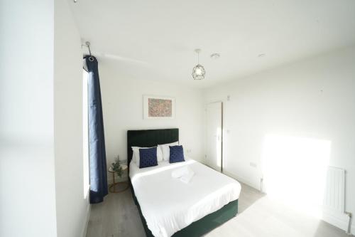a bedroom with a white bed with blue pillows at Ealing Broadway Great Stay 7-Minute Walk from the Underground in Ealing