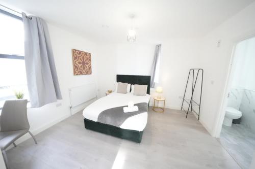 a white bedroom with a bed and a chair at Ealing Broadway Great Stay 7-Minute Walk from the Underground in Ealing