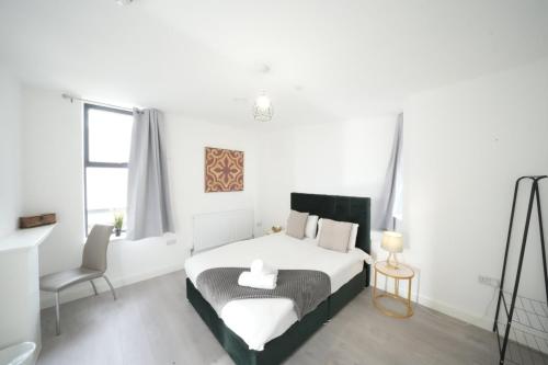 a white bedroom with a bed and a chair at Ealing Broadway Great Stay 7-Minute Walk from the Underground in Ealing