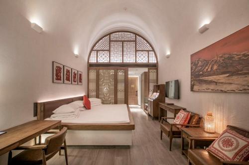 a bedroom with a large bed and a dining room at Wanda Realm Yan'an in Yan'an