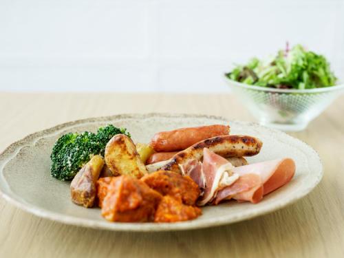 a plate of food with meat and vegetables on a table at Mitsui Garden Hotel Yokohama Minatomirai Premier in Yokohama