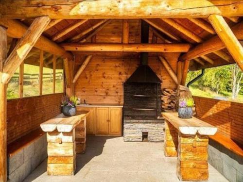 a wooden pavilion with two benches and a fireplace at Villa in Nowy Targ with Mountain Views & Pool in Nowy Targ