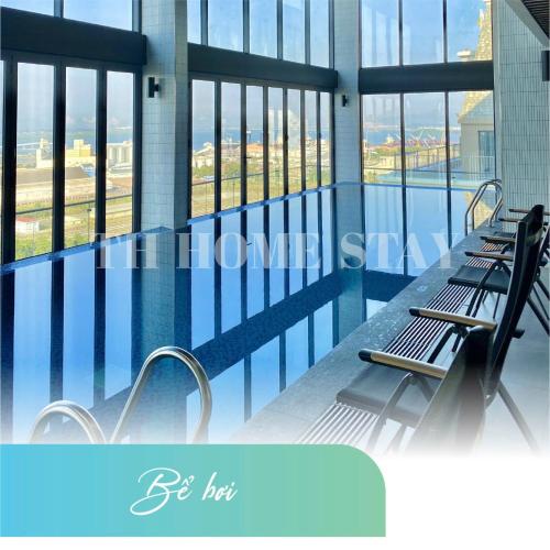 a swimming pool with two benches in a building with windows at Homestay Dragon Castle Bãi Cháy Hạ Long Quảng Ninh in Ha Long