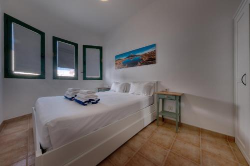 Un dormitorio blanco con una cama y una mesa. en Mar y Ola, en Playa Blanca