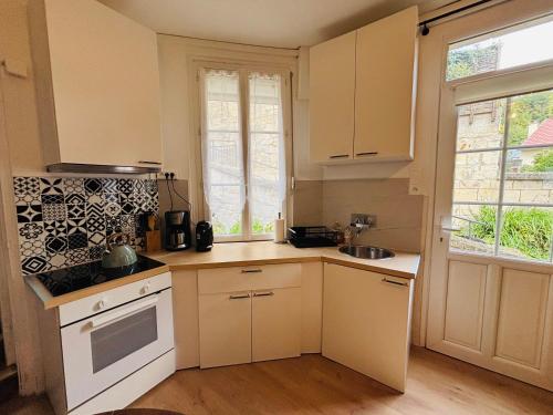 a small kitchen with white cabinets and a sink at L'inattendue in Pierrefonds