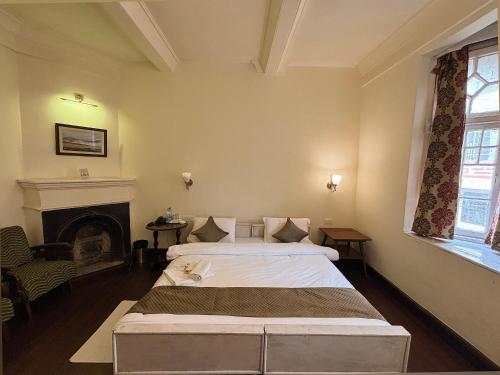 a bedroom with two beds and a fireplace at Pineridge Hotel at Mall Road in Darjeeling