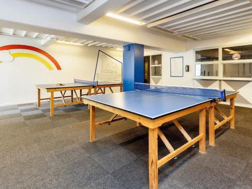 two ping pong tables in a room with a rainbow on the wall at Faaborg Holiday Centre in Fåborg