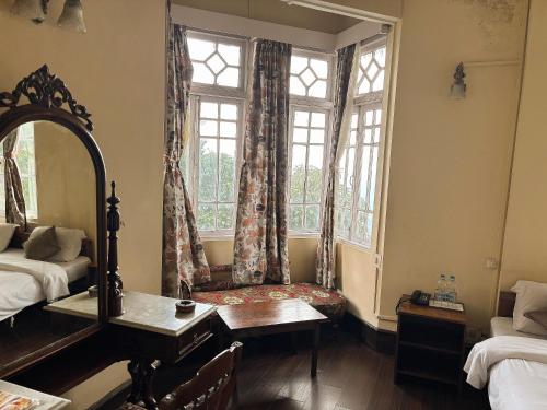 a bedroom with a window with a chair and a mirror at Pineridge Hotel at Mall Road in Darjeeling