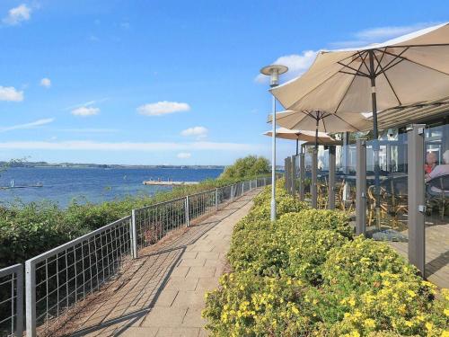a walkway with umbrellas and tables and the water at Faaborg Holiday Centre in Fåborg