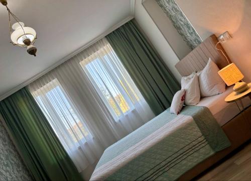 a bedroom with a bed with green curtains at Vashlovani Sweet Home in Dedoplis Tskaro