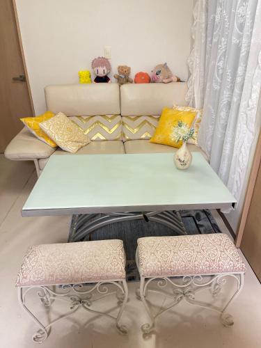 a table and two stools in front of a couch at 望月ハウス101 in Tokyo