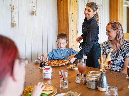 a family sitting around a table eating pizza at Vigsø Holiday Center in Hanstholm