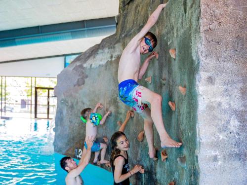a group of kids climbing a rock wall in a pool at Ho Holiday Center in Blåvand