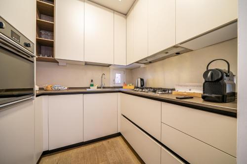 a kitchen with white cabinets and a counter top at PIAZZA MAGGIORE-Luxury Apartment-Elegant Terrace in Bologna