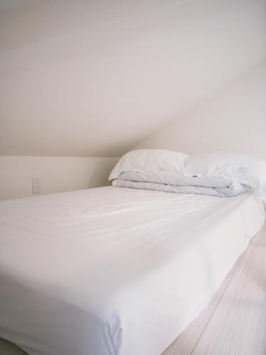 a white bed with white sheets and a pillow at D Regalo in Ichikawa