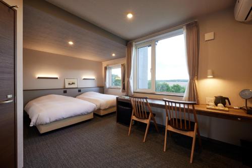 a bedroom with a bed and a desk and a window at Rising Sun Furano in Kami-furano