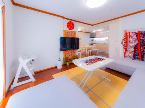 a living room with a white table and a couch at 琉球乃風-プチョヘンザ- in Uruma
