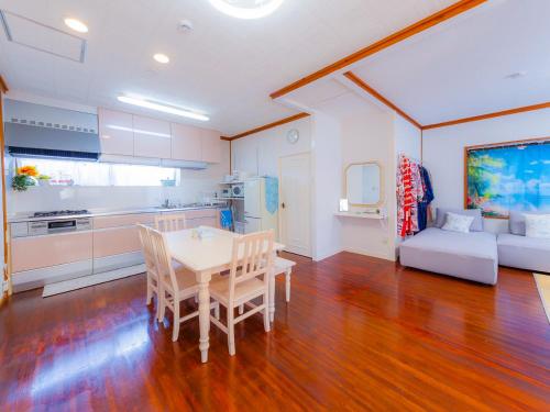 a kitchen and living room with a table and chairs at 琉球乃風-プチョヘンザ- in Uruma