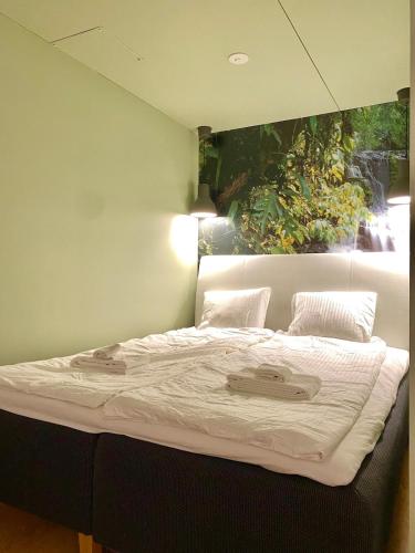 a large bed in a room with a painting on the wall at Ellis Seaside Suite in Helsinki