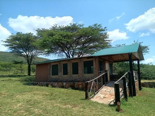 a small house with a green roof in a field at Miliki Maasai Mara in Sekenani
