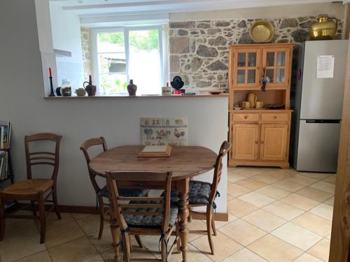a kitchen with a table and chairs and a refrigerator at Maison Normande in Saint-Michel-de-la-Pierre