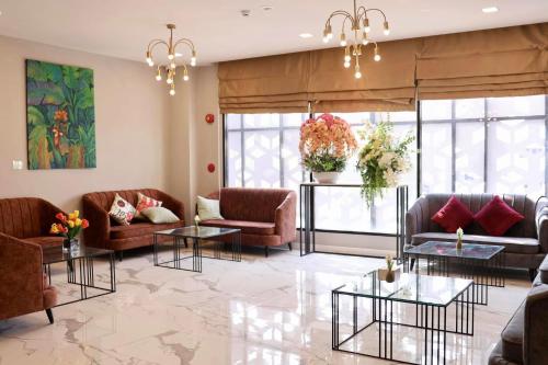 a living room with couches and tables and windows at Shewin de Bangkok in Ban Bang Bamru