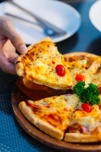 a person holding a slice of pizza on a plate at Shewin de Bangkok in Ban Bang Bamru