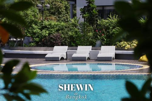 a group of lounge chairs next to a swimming pool at Shewin de Bangkok in Ban Bang Bamru