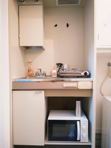 a small kitchen with a sink and a microwave at D Regalo in Ichikawa