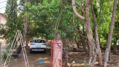 a white car parked in a yard with trees at Tripathi Villa in Murbād
