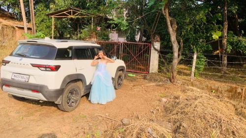 a woman in a blue dress standing next to a car at Tripathi Villa in Murbād