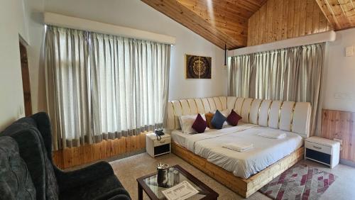 a bedroom with a bed and a couch and a table at The Himalayan Apple Flower Resort with Mountain View in Katrain