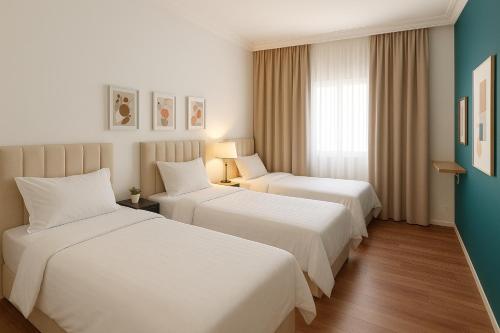 a hotel room with two beds and a window at شقة 7 هادئة بتصميم انيق ثلاث غرف ودخول ذاتي in Al Khobar