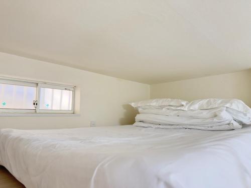 a white bed with white sheets and a window at D Regalo in Ichikawa