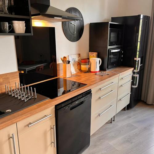 a kitchen with black appliances and a wooden counter top at Les Capucines, comme chez soi, loin de chez soi in Aubenas