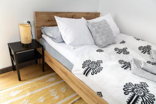 a bed with a black and white comforter and pillows at Apartamenty u Jakubika in Krynica Zdrój