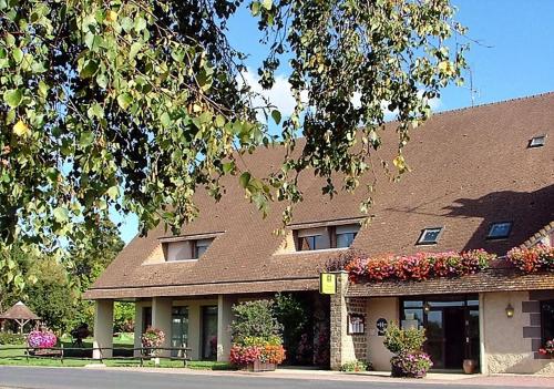 un edificio con flores y plantas delante de él en Auberge d'Andaines, en La Ferté-Macé