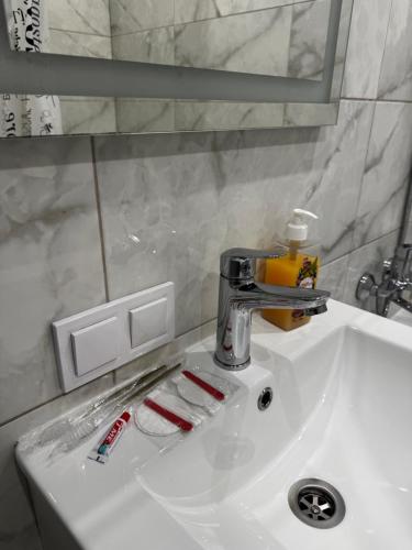a bathroom sink with a faucet and toothbrushes at 1кімнатна VIP Ковпака Сумської Тероборони in Sumy