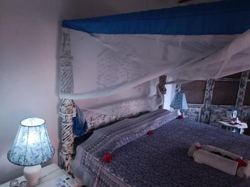 a bedroom with a bed with a canopy and a lamp at Aquarius Club in Watamu