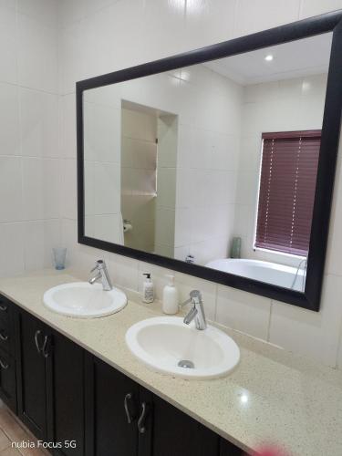 a bathroom with two sinks and a large mirror at Feather Tree Bed and Breakfast in Centurion