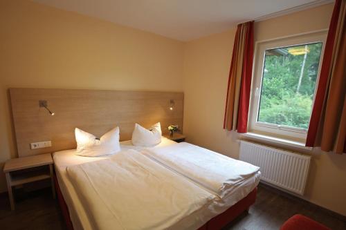 Schlafzimmer mit einem Bett mit weißer Bettwäsche und einem Fenster in der Unterkunft Ferienzentrum Trassenmoor in Trassenheide