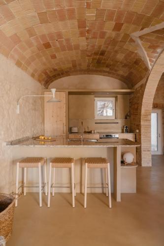a kitchen with a counter and stools in a room at Casa boutique a Vilamacolum in Vilamacolum