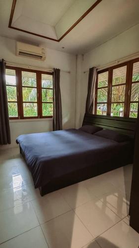 a bedroom with a large bed with two windows at Kood Life in Ko Kood