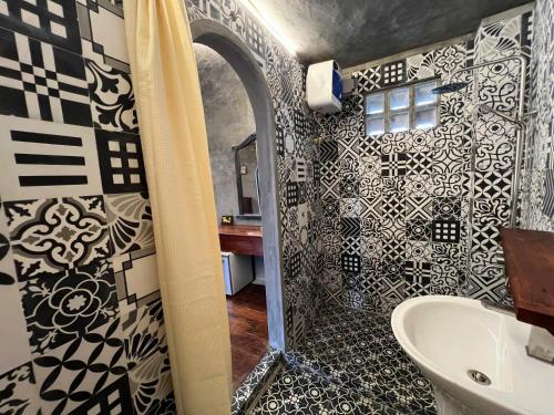 une salle de bain avec des murs carrelés en noir et blanc et une douche dans l'établissement Tre Hội An Heritage Inspired Homestay & Café, à Thanh Ðông (1)