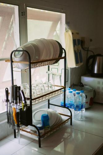 a shelf in a kitchen with dishes and water bottles at Kood Life in Ko Kood