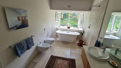 a bathroom with two toilets and a tub and a sink at Tranquil Stylish Home with Nature Pool near Reserve in Somerset West