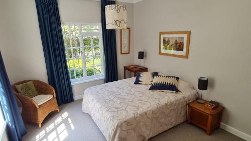 a bedroom with a bed and a chair and a window at Tranquil Stylish Home with Nature Pool near Reserve in Somerset West