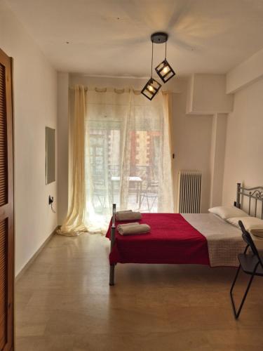a bedroom with a red bed and a window at Kavala central studio in Kavala